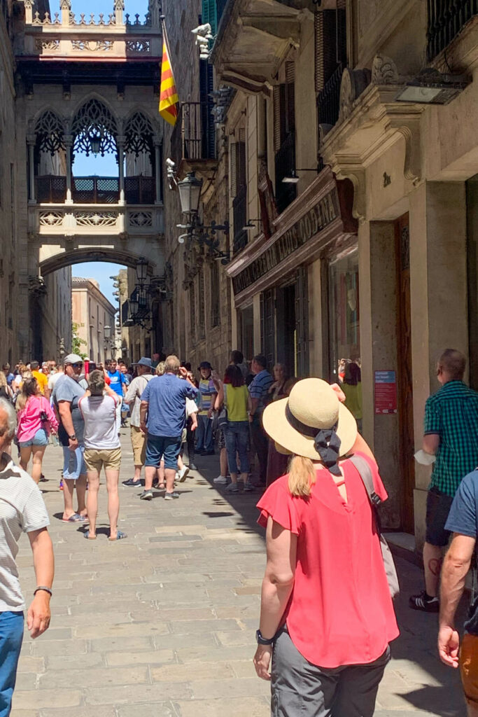A woman in a sun hat looking down a tourist filled street in Barcelona.